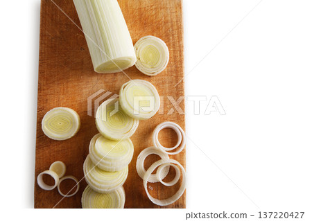 Cooking healthy food. Sliced and chopped leek on wooden cutting board isolated at white background Cooking healthy food. Sliced and chopped leek on wooden cutting board isolated at white background 137220427
