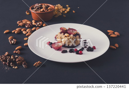 Healthy eating, dieting and detox concept - wholegrain fresh oatmeal porridge with fruits, berries and nuts on dark background. 137220441