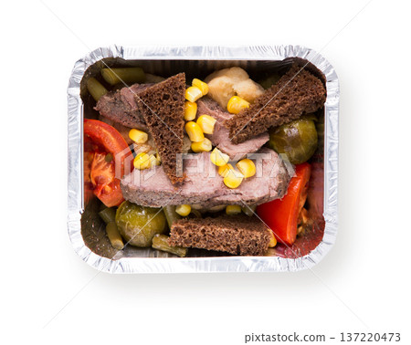 Healthy food in foil box isolated at white background. Daily slimming menu. Organic restaurant food take away and delivery. Steamed meat with vegetable salad, rye bread and corn, top view Healthy food in foil box isolated at white background. Daily slimming menu. Organic restaurant food take away and delivery. Steamed meat with vegetable salad, rye bread and corn, top view 137220473