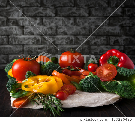 Cooking healthy vegetarian food on dark background. Fresh organic vegetables on pita flatbread. Natural food with copy space. Cooking healthy vegetarian food on dark background. Fresh organic vegetables on pita flatbread. Natural food with copy space. 137220480