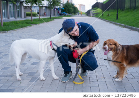 A man hugs his two dogs while on a walk. A man hugs his two dogs while on a walk. 137220496