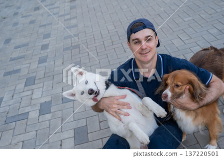 A man hugs his two dogs while on a walk.  137220501