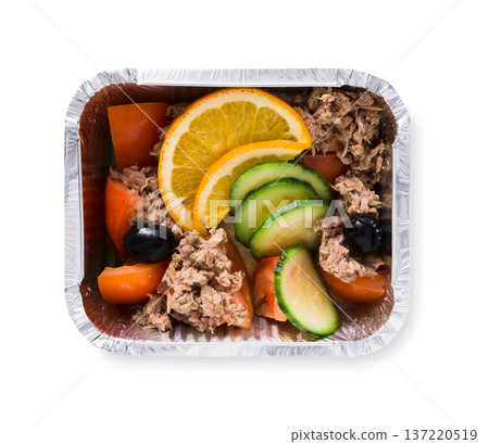 Healthy lunch in foil take away container, diet concept. Salad with chopped steamed meat, fresh tomatoes and cucumber, black olives and orange. Isolated on white background, closeup 137220519