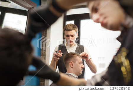 Making modern hairstyle in male hair salon. Barbers using trimmer in barbershop. Making modern hairstyle in male hair salon. Barbers using trimmer in barbershop. 137220548