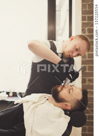 Barber in barbershop make beard haircut, shaving. Hairstyle in male hair salon Barber in barbershop make beard haircut, shaving. Hairstyle in male hair salon 137220554