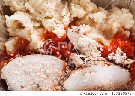 A comforting dish includes tender slices of seasoned chicken topped with rich tomato sauce and served alongside fluffy couscous. Perfect for a satisfying lunch or dinner. 137220573