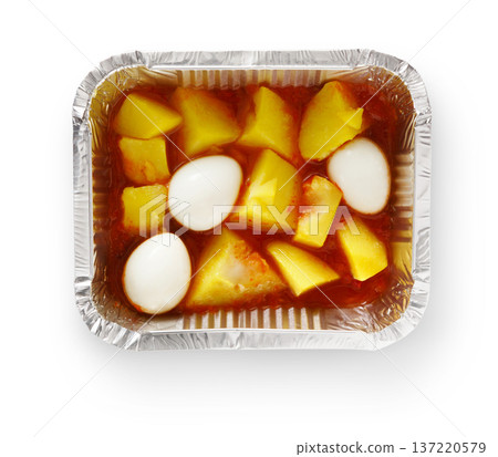 This dish showcases chunks of yellow potatoes and white eggs in a rich, tangy sauce, all neatly arranged in a foil tray. Perfect for a hearty and comforting meal. 137220579