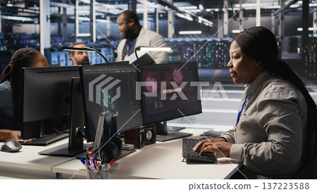 Panicked system administrator in data center reacting to spyware warning on PC screen, launching emergency response protocol. Worker trying to repair hacked equipment systems, camera A 137223588