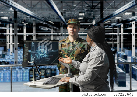Army tech expert in data center presenting tactical options to commander based on predictive AI models analysis. Server farm workers reading artificial intelligence reports Army tech expert in data center presenting tactical options to commander based on predictive AI models analysis. Server farm workers reading artificial intelligence reports 137223645