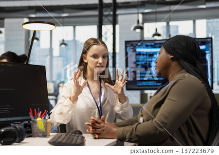 Junior dev and female programmer gossiping about coworkers, having fun. Group of women engaged in workplace chat during job shift break, exchanging office news about colleagues 137223679