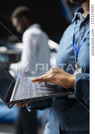 Close up of female supervisor overseeing staff doing AI automatization, machine learning for servers infrastructure. Data center specialist managing operations with artificial intelligence. Close up of female supervisor overseeing staff doing AI automatization, machine learning for servers infrastructure. Data center specialist managing operations with artificial intelligence. 137223683