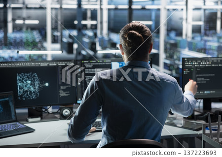Engineer in data center using AI LLM assistant to perform maintenance on infrastructure rigs. Server room worker using large language model chatbot to do backup on storage arrays Engineer in data center using AI LLM assistant to perform maintenance on infrastructure rigs. Server room worker using large language model chatbot to do backup on storage arrays 137223693