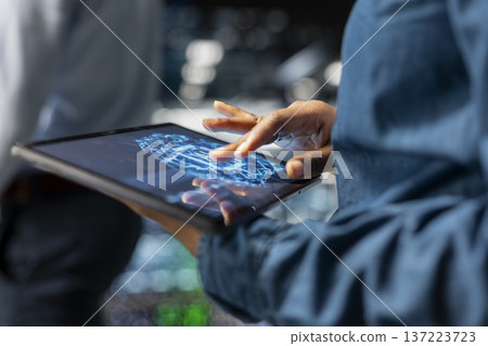 Close up of data center technician using tablet for maintenance on server rigs, handling AI processing tasks. Server hub data scientist managing storage arrays supporting deep learning tech. 137223723
