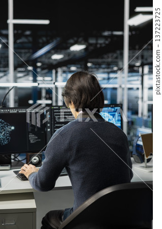 System administrator in data center optimizing hardware for AI tasks, increasing workloads. Man in server hub automating system diagnostics using deep learning predictions 137223725