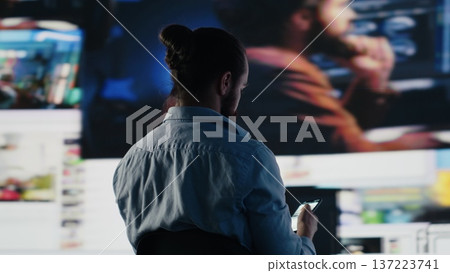 Young man stares at smartphone in distress symbolizing toxic impact of social media on mental health. Likes, posts and endless scrolling lead to stress and depression. Overwhelmed user. Camera A. 137223741