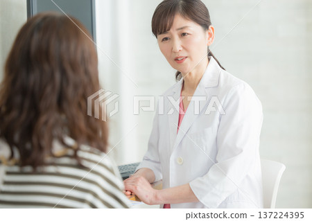 A woman in a white coat explaining to a patient 137224395