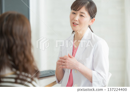 A woman in a white coat explaining to a patient A woman in a white coat explaining to a patient 137224400