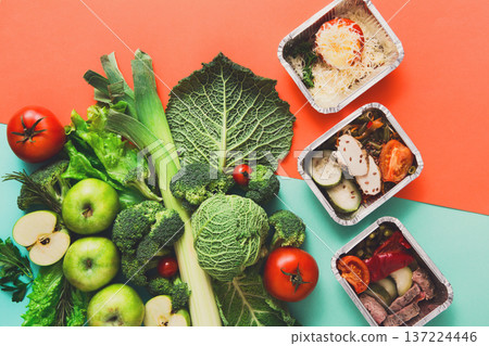 Healthy meals in lunch boxes with green vegetables and fruits. Diet, detox and healthy food concept - top view flat lay on bright background. Ingredients for salad Healthy meals in lunch boxes with green vegetables and fruits. Diet, detox and healthy food concept - top view flat lay on bright background. Ingredients for salad 137224446