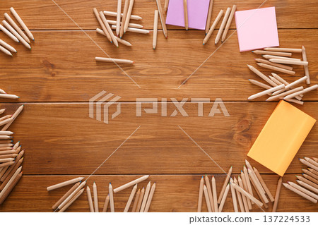 Colorful pencils and sticky notes are scattered artistically on a rustic wooden table, providing an inviting atmosphere for creativity and brainstorming. Ideal for artistic planning and organization. Colorful pencils and sticky notes are scattered artistically on a rustic wooden table, providing an inviting atmosphere for creativity and brainstorming. Ideal for artistic planning and organization. 137224533