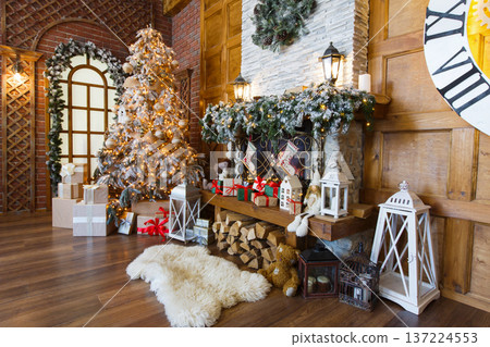 Beautiful christmas interior. Warm room with fireplace, decorated christmas tree, lots of presents and huge clock on wooden wall. Cozy home for winter holidays, copy space, side view 137224553