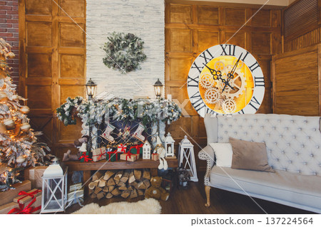 Beautiful holdiay living room. Fireplace decorated with fir tree wreath and garland and soft cozy gray couch. Winter holiday design and decorations background Beautiful holdiay living room. Fireplace decorated with fir tree wreath and garland and soft cozy gray couch. Winter holiday design and decorations background 137224564