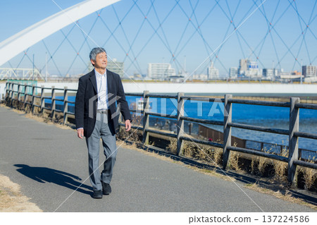 Man walking along the riverbank Man walking along the riverbank 137224586