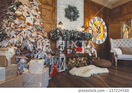 Beautiful christmas interior. Warm room with fireplace, decorated christmas tree, lots of presents and huge clock on wooden wall. Cozy home for winter holidays, copy space, side view Beautiful christmas interior. Warm room with fireplace, decorated christmas tree, lots of presents and huge clock on wooden wall. Cozy home for winter holidays, copy space, side view 137224588