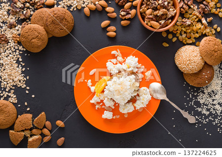 Healthy breakfast, dieting and detox concept - cottage cheese on plate with nuts and cookies on dark background. Still life, flat lay, top view 137224625