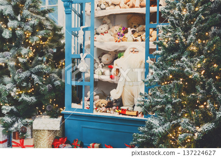 Christmas magical atmosphere background. Modern interior design for winter holidays. Pine trees decorated with shining lights, showcase with toys and present boxes Christmas magical atmosphere background. Modern interior design for winter holidays. Pine trees decorated with shining lights, showcase with toys and present boxes 137224627