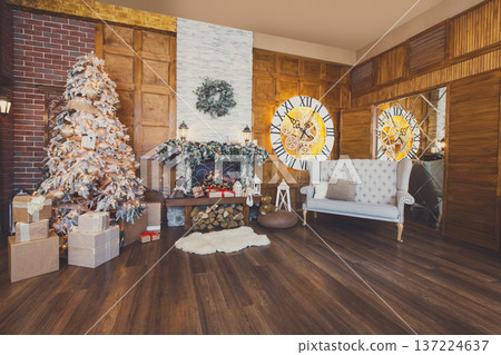 Beautiful christmas interior. Warm room with fireplace, decorated christmas tree, lots of presents and huge clock on wooden wall. Cozy home for winter holidays, copy space 137224637