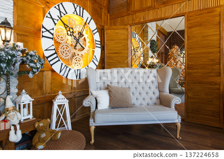 Beautiful holdiay living room. Big magical clock on wooden wall and soft cozy gray couch. Winter holiday design and decorations background 137224658