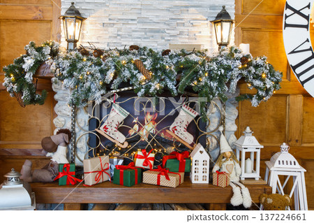 Beautiful holdiay living room. Fireplace decorated with fir tree wreath and garland. Lots of presents and christmas stockings under mantelpiece. Winter holiday design and decorations background Beautiful holdiay living room. Fireplace decorated with fir tree wreath and garland. Lots of presents and christmas stockings under mantelpiece. Winter holiday design and decorations background 137224661