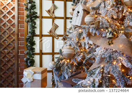 Christmas magic background. Beautiful decorated white xmas tree near huge window. Shining lights, baubles and garland. Winter holidays magic atmosphere. Modern design and decorations, copy space 137224664
