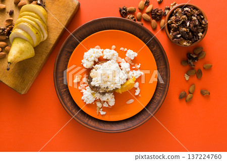 Healthy breakfast, dieting and detox concept - fresh cottage cheese on plate, bowl with nuts and wood board with fruit on bright background. Still life, flat lay, top view, copy space 137224760