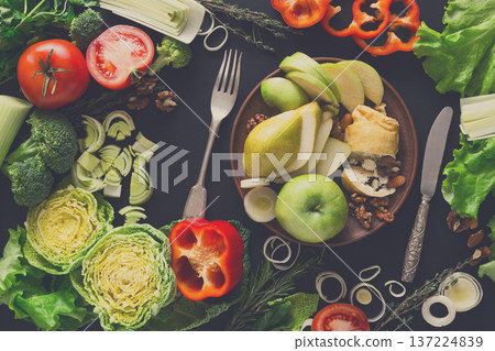 Healthy eating concept. Fresh organic meals and low-fat dessert on brown clay plate at black background. Strudel with cottage-cheese, nuts, apple, pear and vegetables Healthy eating concept. Fresh organic meals and low-fat dessert on brown clay plate at black background. Strudel with cottage-cheese, nuts, apple, pear and vegetables 137224839