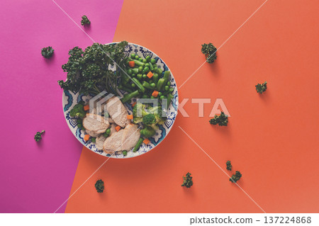 Healthy food delivery, diet nutrition. Cut organic green steamed vegetables and slices of chicken on bright geometric background, top view, copy space 137224868