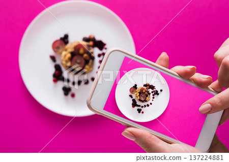 Top view close-up of female hands making flat lay food photo with phone for restaurant menu or social network. Oatmeal porridge on pink background, mockup, template, copy space, shallow depth of field Top view close-up of female hands making flat lay food photo with phone for restaurant menu or social network. Oatmeal porridge on pink background, mockup, template, copy space, shallow depth of field 137224881