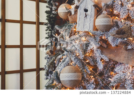 Christmas magic background. Beautiful decorated white xmas tree near huge window. Shining lights, baubles and garland. Winter holidays magic atmosphere. Modern design and decorations, copy space Christmas magic background. Beautiful decorated white xmas tree near huge window. Shining lights, baubles and garland. Winter holidays magic atmosphere. Modern design and decorations, copy space 137224884