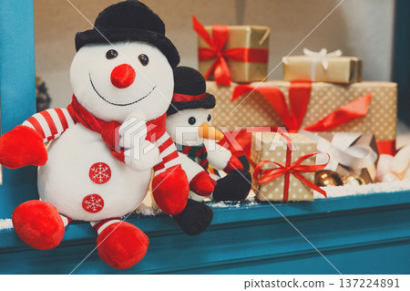 Cozy winter holidays background. Funny toy snowmen and presents waiting for christmas on blue wooden showcase . Joyful and magical atmosphere of new year eve, copy space Cozy winter holidays background. Funny toy snowmen and presents waiting for christmas on blue wooden showcase . Joyful and magical atmosphere of new year eve, copy space 137224891