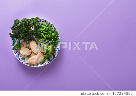 Healthy food delivery, diet nutrition. Cut organic green steamed vegetables and slices of chicken on bright violet background, top view, copy space Healthy food delivery, diet nutrition. Cut organic green steamed vegetables and slices of chicken on bright violet background, top view, copy space 137224893