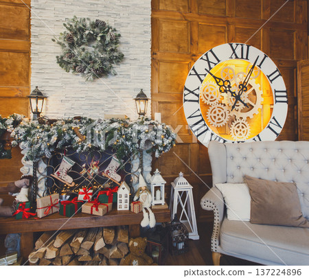 Beautiful holdiay living room. Fireplace decorated with fir tree wreath and garland and soft cozy gray couch. Winter holiday design and decorations background Beautiful holdiay living room. Fireplace decorated with fir tree wreath and garland and soft cozy gray couch. Winter holiday design and decorations background 137224896