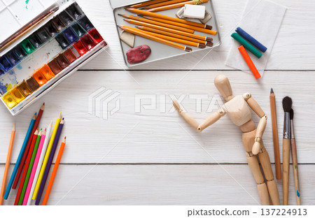 Drawing tools, stationary supplies, workplace of artist. Paints and wooden painter man with brushes on white desk, top view, flat lay, objects 137224913