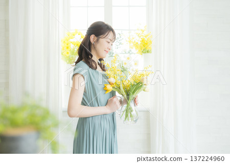 女子在窗台上插花。 女子在窗台上插花。 137224960