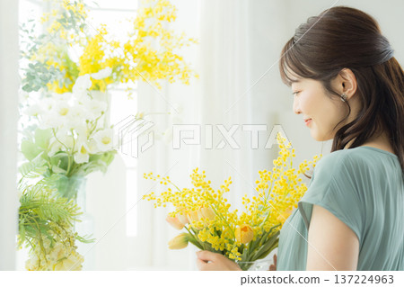 Woman arranging flowers on the windowsill Woman arranging flowers on the windowsill 137224963