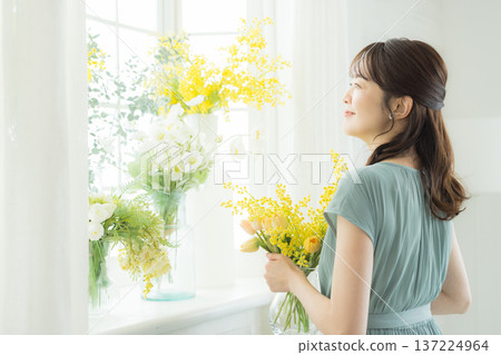 女子在窗台上插花。 女子在窗台上插花。 137224964