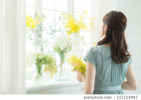 女子在窗台上插花。 女子在窗台上插花。 137224965
