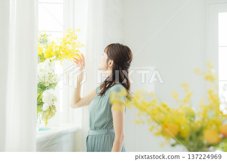 Woman arranging flowers on the windowsill 137224969
