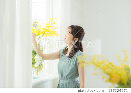 Woman arranging flowers on the windowsill 137224971