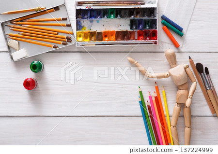 Workplace of artist. Paints and wooden painter man with brushes on white desk, top view, flat lay, objects Workplace of artist. Paints and wooden painter man with brushes on white desk, top view, flat lay, objects 137224999