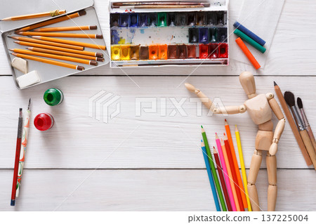Workplace of artist. Paints and wooden painter man with brushes on white desk, top view, flat lay, objects Workplace of artist. Paints and wooden painter man with brushes on white desk, top view, flat lay, objects 137225004